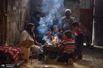 خانواده ای دور هیزم در حال سوختن در خان یونس غزه فلسطین گرم می شوند. عکس: Yousef Masoud/via ZUMA Wire

