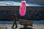 یک پسر افغان گاری حاوی پشمک را در خیابانی در کابل می کشد.